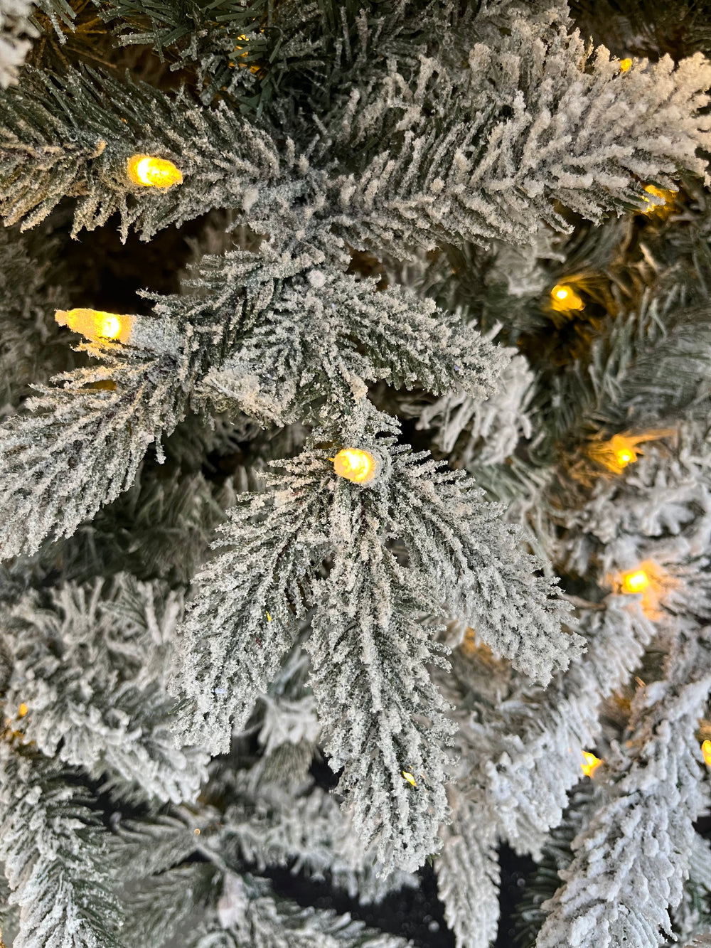 7.5' Durham Flocked Pre-Lit LED Artificial Christmas Tree, close-up of foliage, with clear lights.